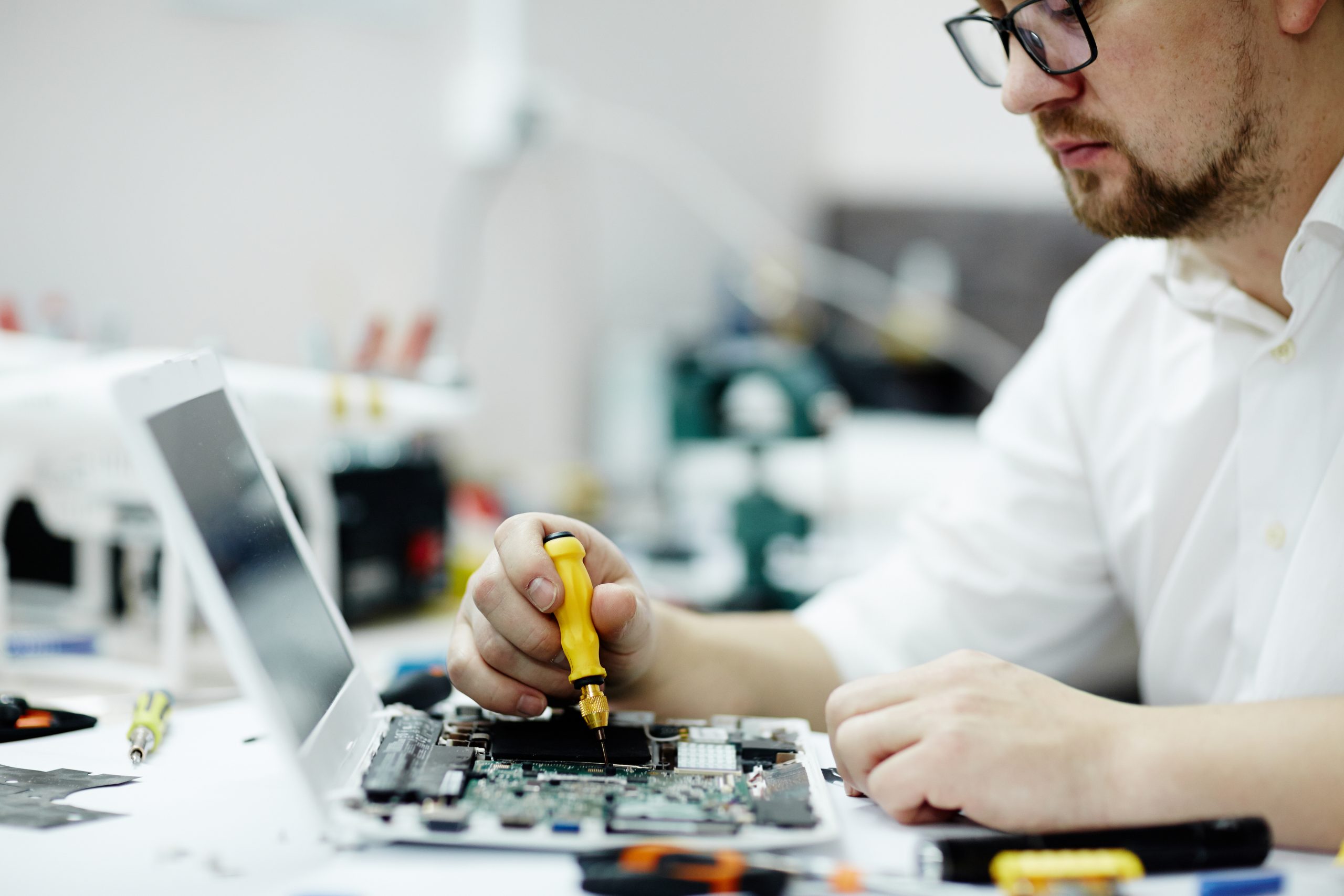 Portrait of modern working on assembling circuit board using screwdriver and tools on table in maintenance shop